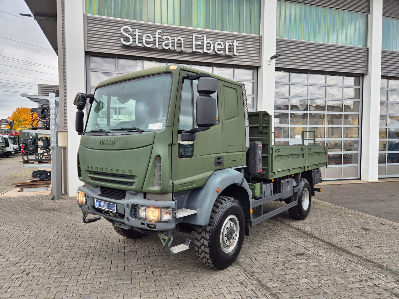 Iveco Eurocargo ML100E22WM-BW 4x4 Pritsche L-Haus Bett - Φορτηγό με ανοιχτή καρότσα: φωτογραφία 1 Iveco Eurocargo ML100E22WM-BW 4x4 Pritsche L-Haus Bett - Φορτηγό με ανοιχτή καρότσα: φωτογραφία 1
